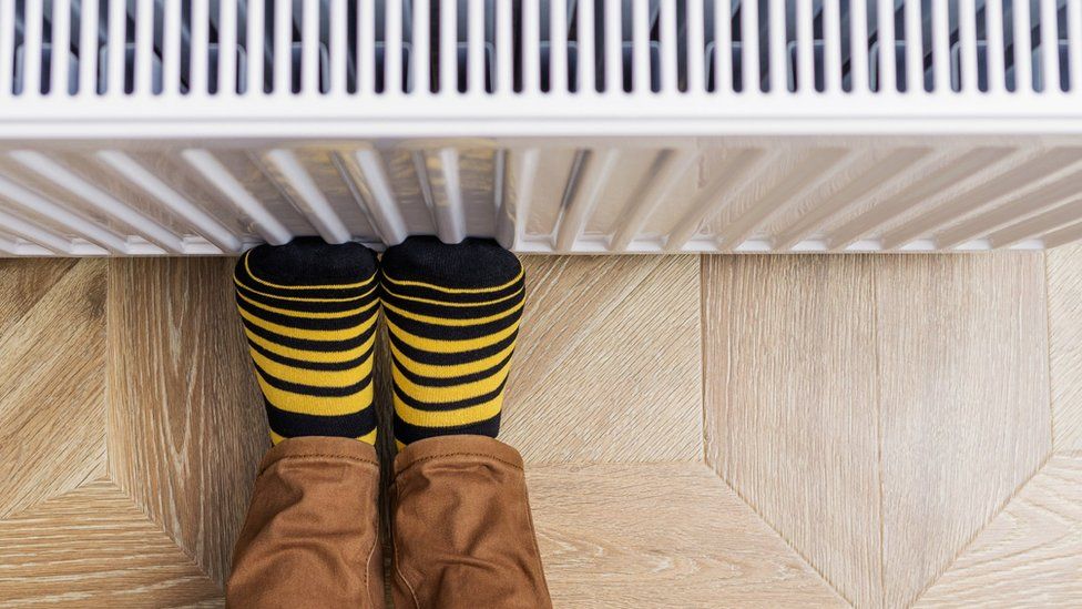 A person rests their feet against a radiator