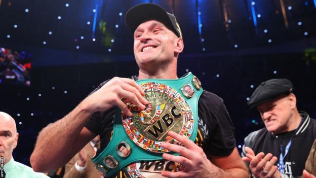 Tyson Fury smiles with his WBC belt around his shoulders