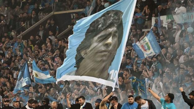 A flag with Diego Maradona's face on it is waved